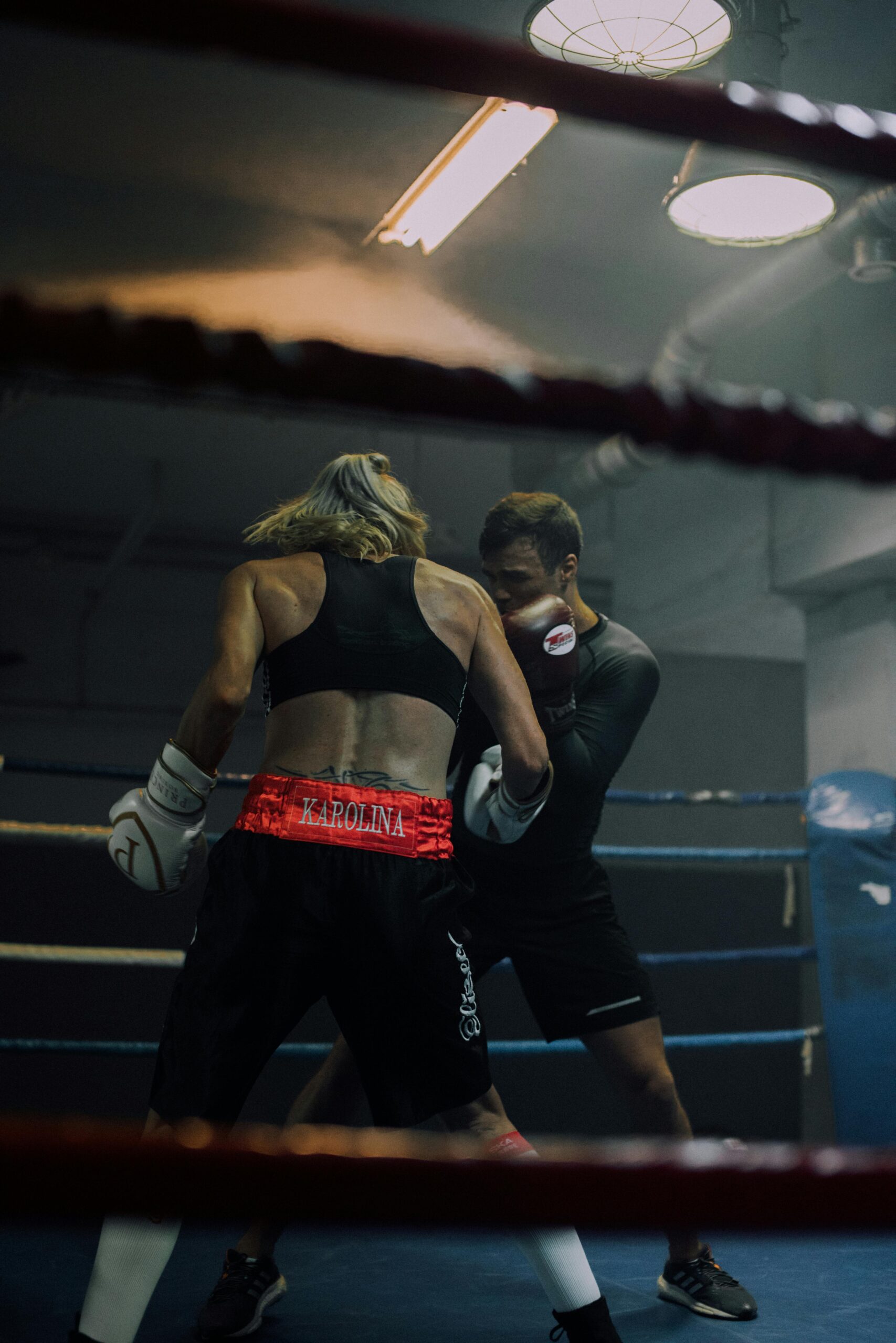 Two athletes sparring in a gym boxing ring, showcasing strength and focus.