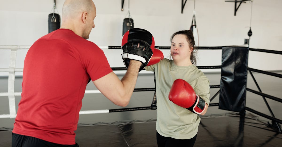 A woman with Down syndrome trains with a bald boxing coach in a gym.