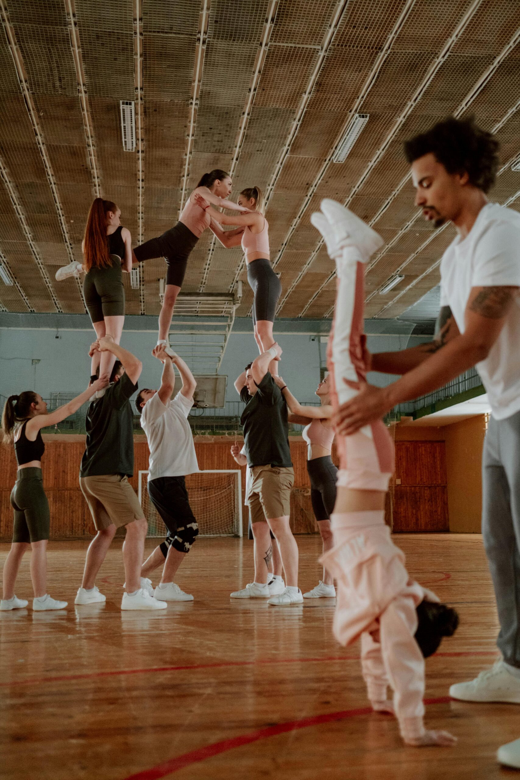 Boy balancing on a gymnastics beam with a coach guiding him.