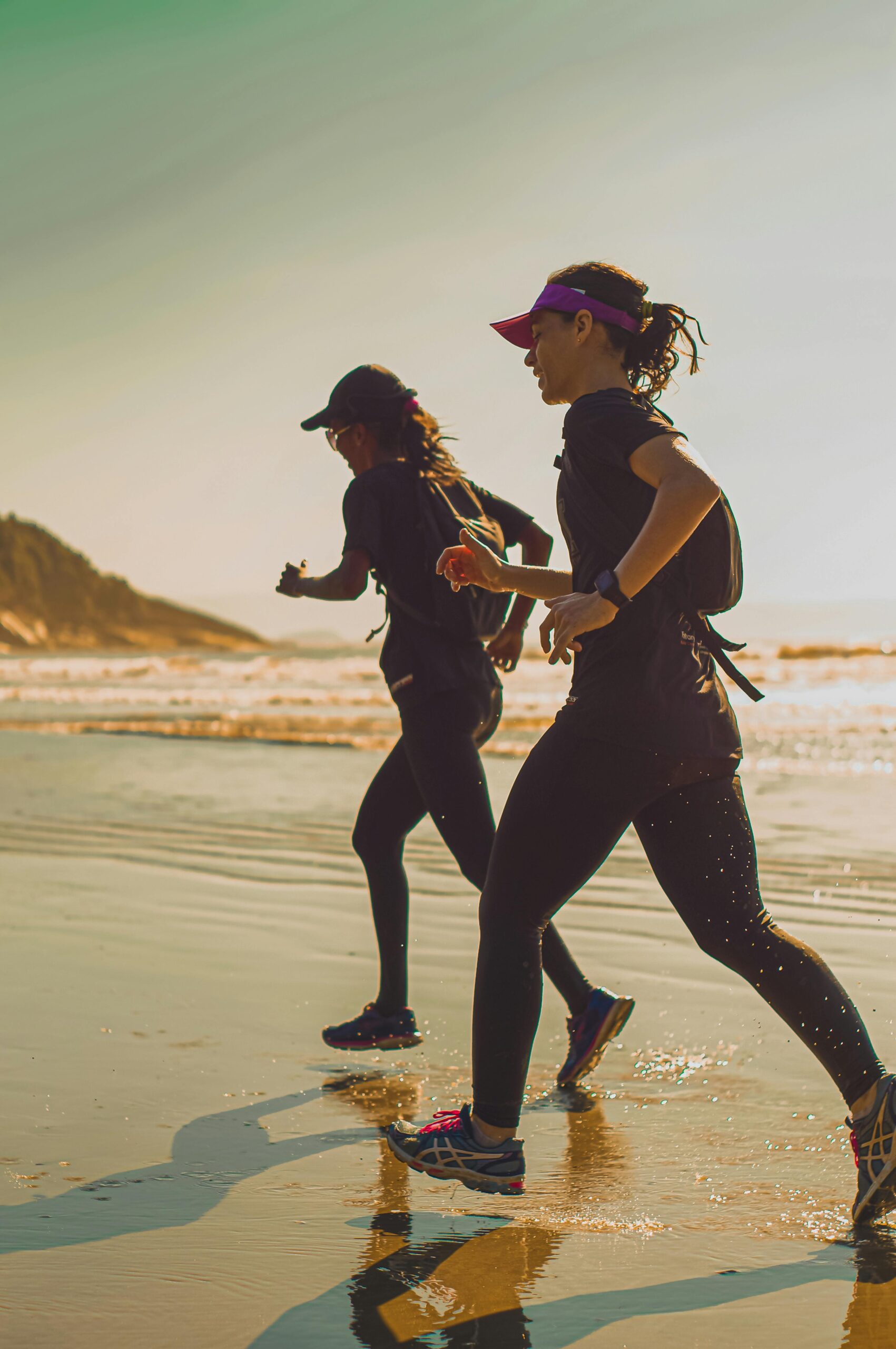 Two women jogging along a beach at sunrise, capturing a sense of freedom and vitality.