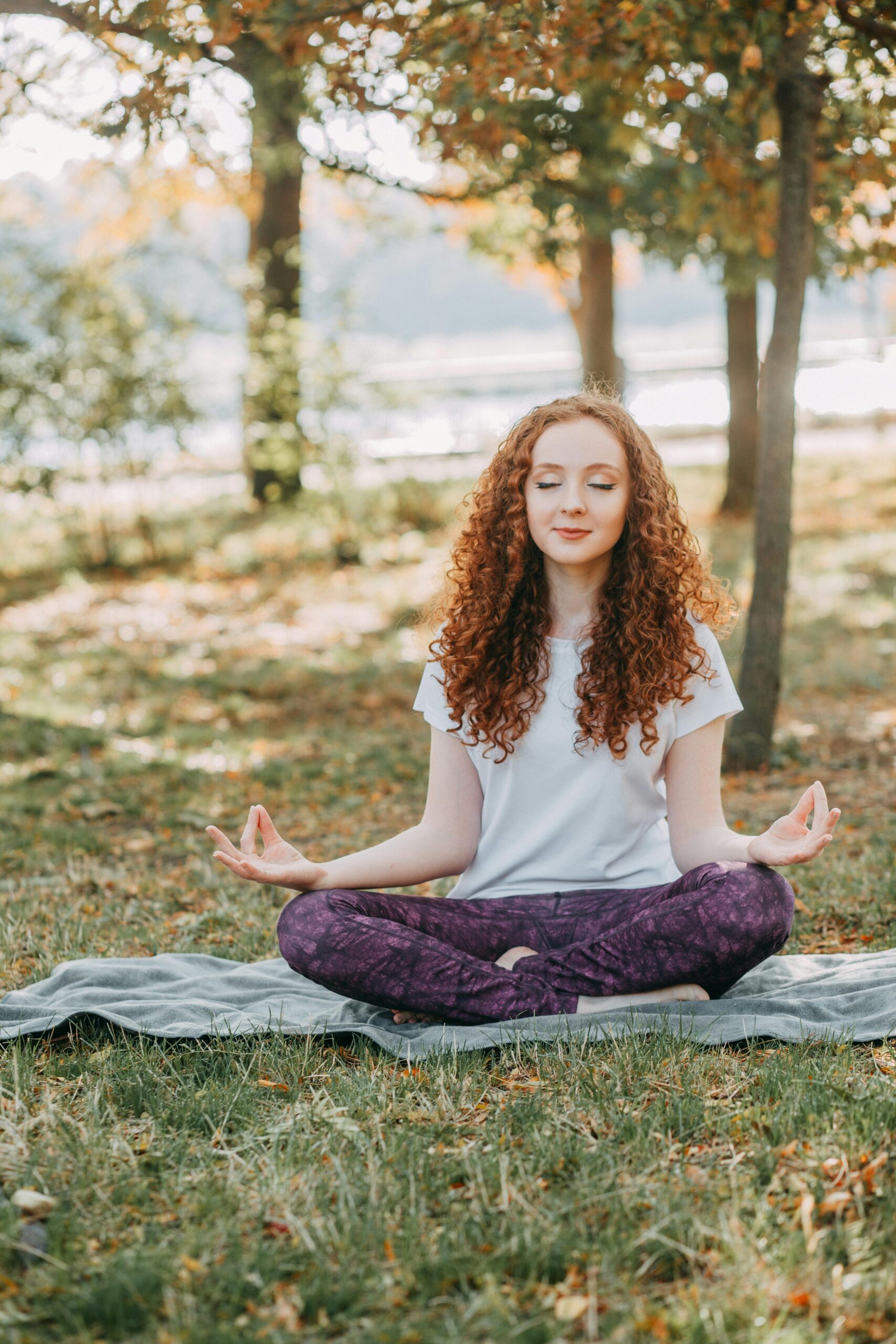 Woman meditating in a serene park during springtime, fostering relaxation and mental wellness.