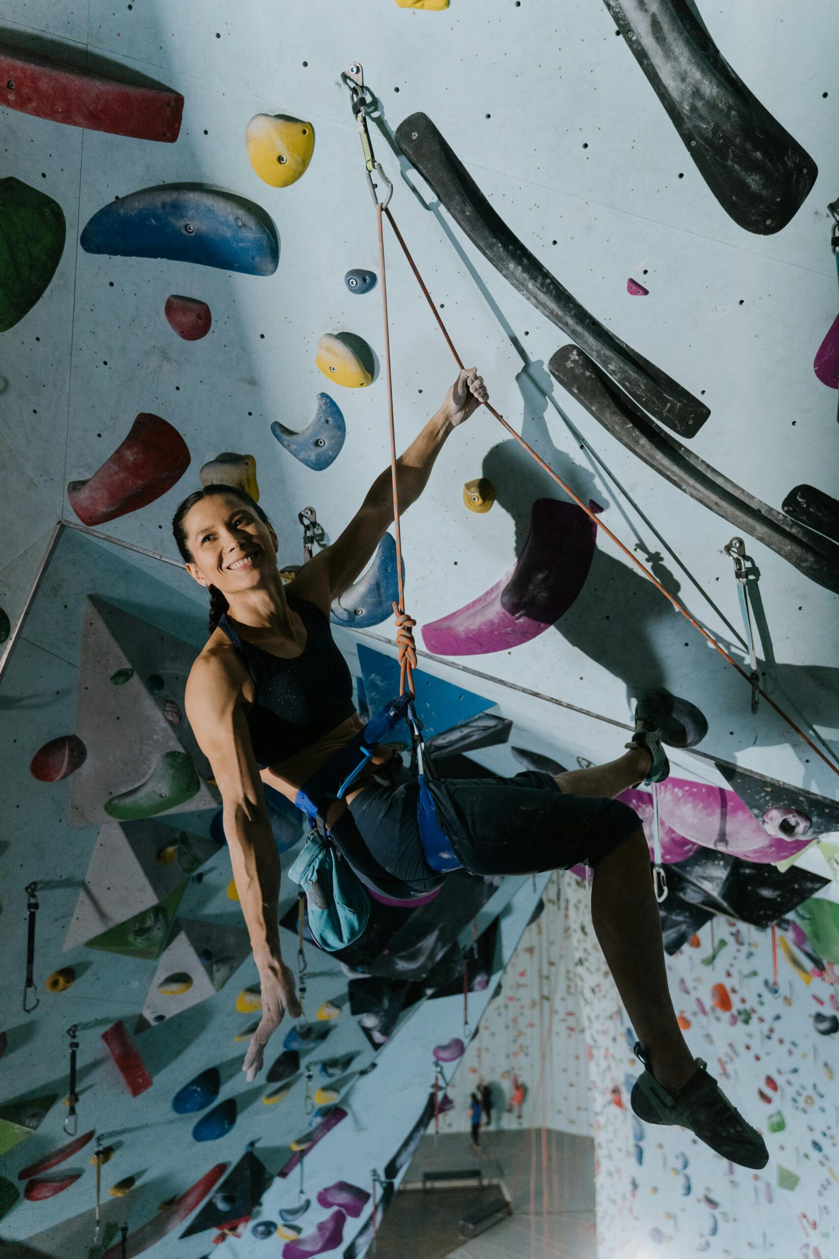 A woman engaged in indoor rock climbing, showcasing strength and skill on a colorful climbing wall.