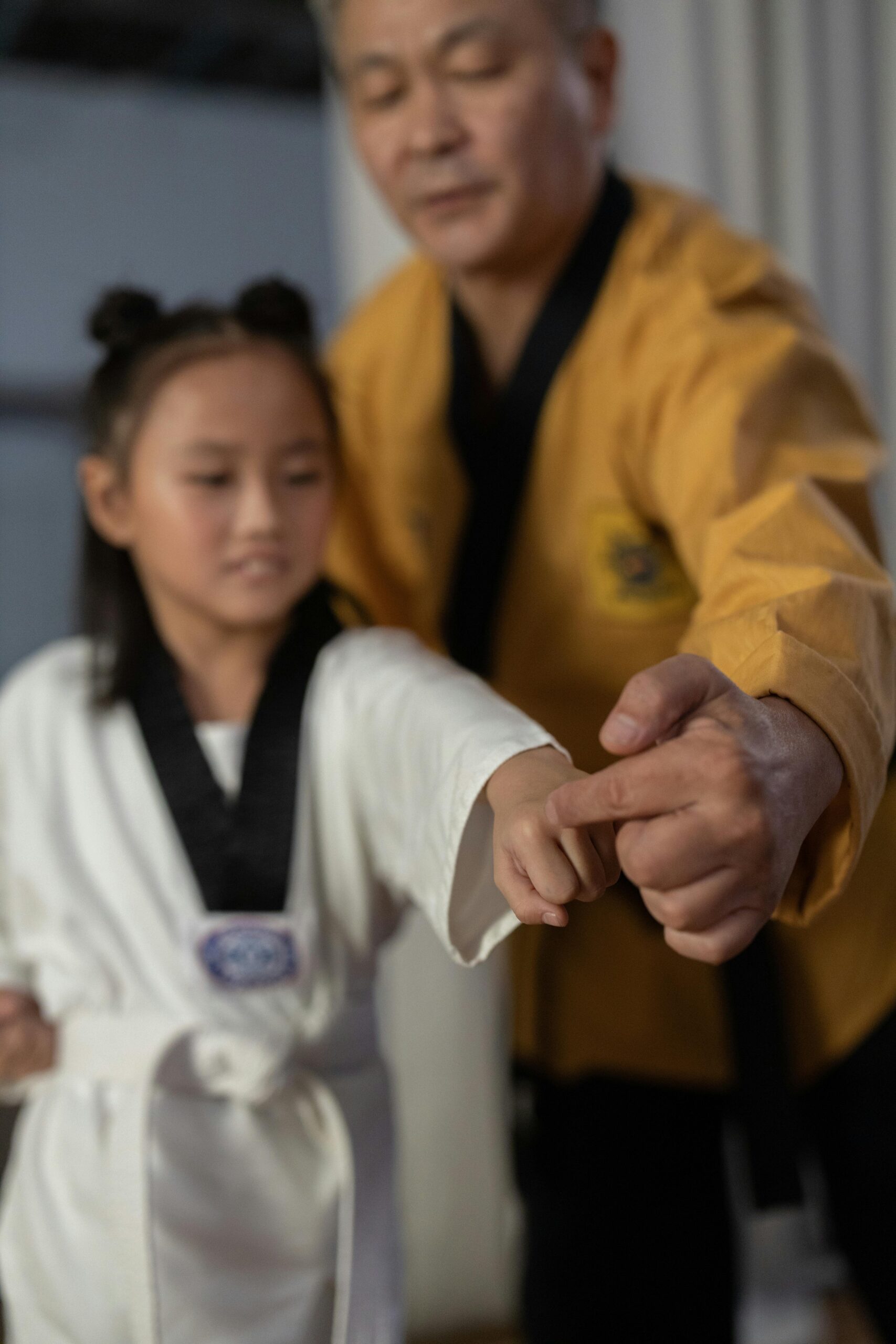 A martial arts instructor helps a young student with her karate stance in class.